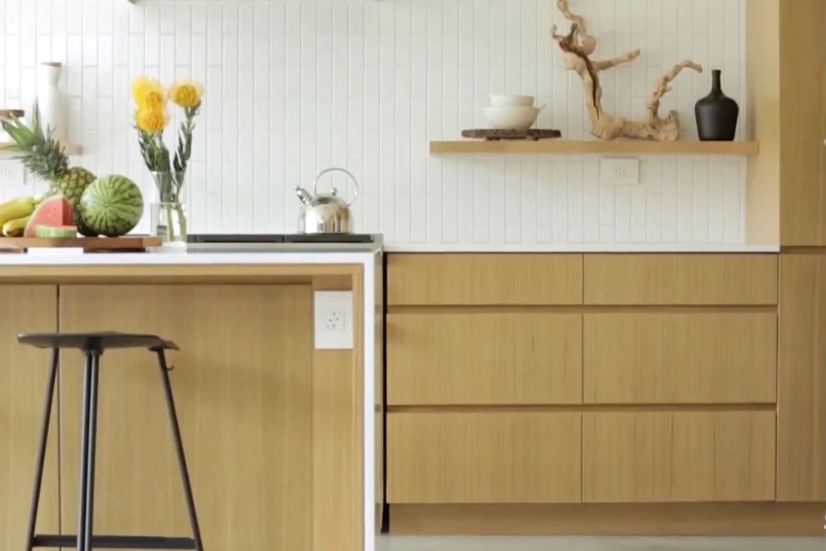 Svetla moderna kuhinja sa drvenim elementima, belom zidnom oblogom, otvorenom policom i voćem na pultu